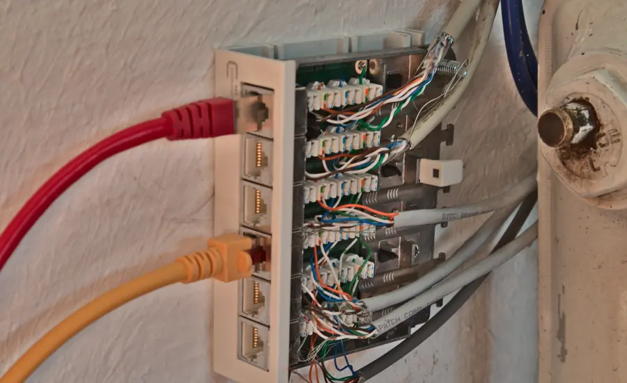 Wandmontiertes Cat-6A-Patchpanel mit aufgelegten Adernpaaren und zwei angesteckten Patchkabeln