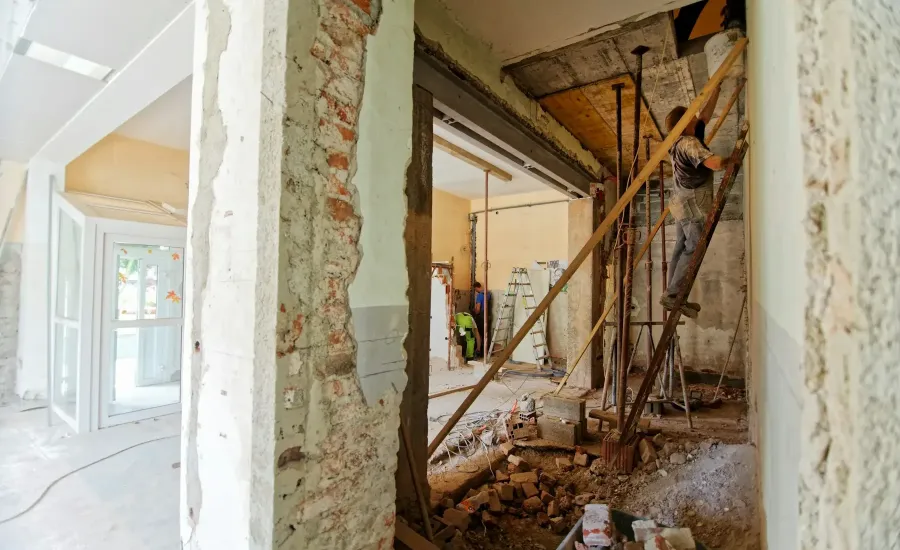 Handwerker an einer Wandöffnung im entkernten Raum – Fenster austauschen bei der Sanierung planen