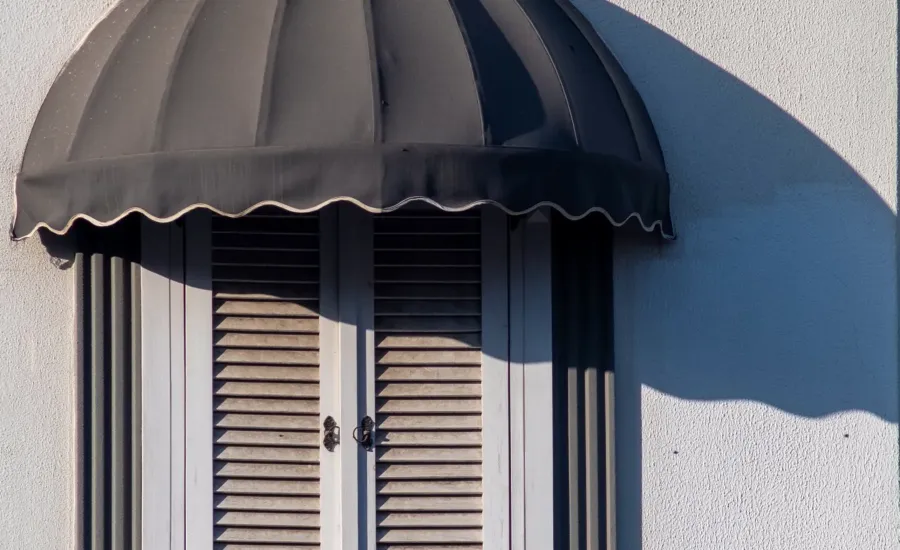 Markise und geschlossene Fensterläden am Haus – Hitzeschutz, um das Haus bei Sommerhitze kühl zu halten